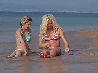 Two playful bikini girls get naked on the beach
